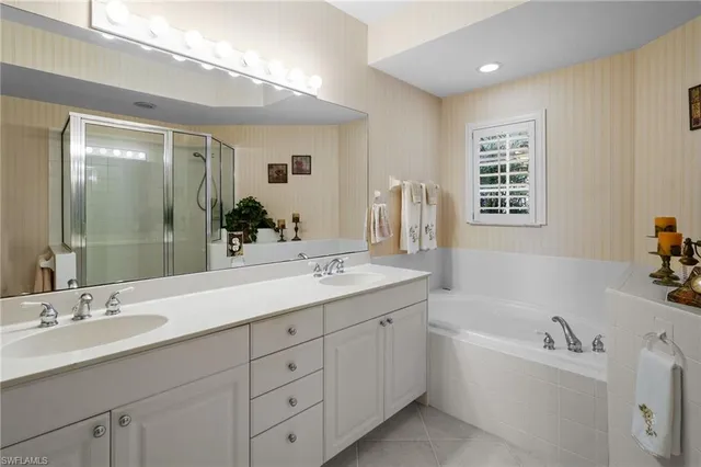a bathroom with a tub double vanity sink and mirror