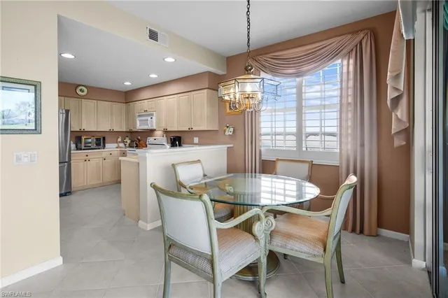 a dining room with stainless steel appliances kitchen island granite countertop a table chairs and a refrigerator