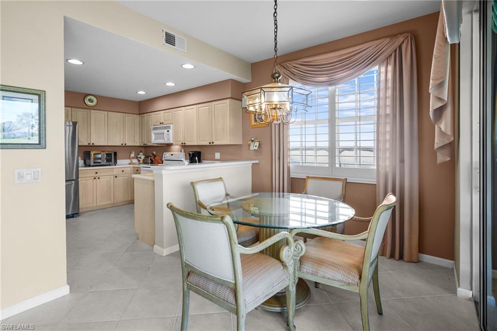 23081 Rosedale Drive, Unit 101 Estero, FL 34135 - Photo 8 of 38 a dining room with stainless steel appliances kitchen island granite countertop a table chairs and a refrigerator