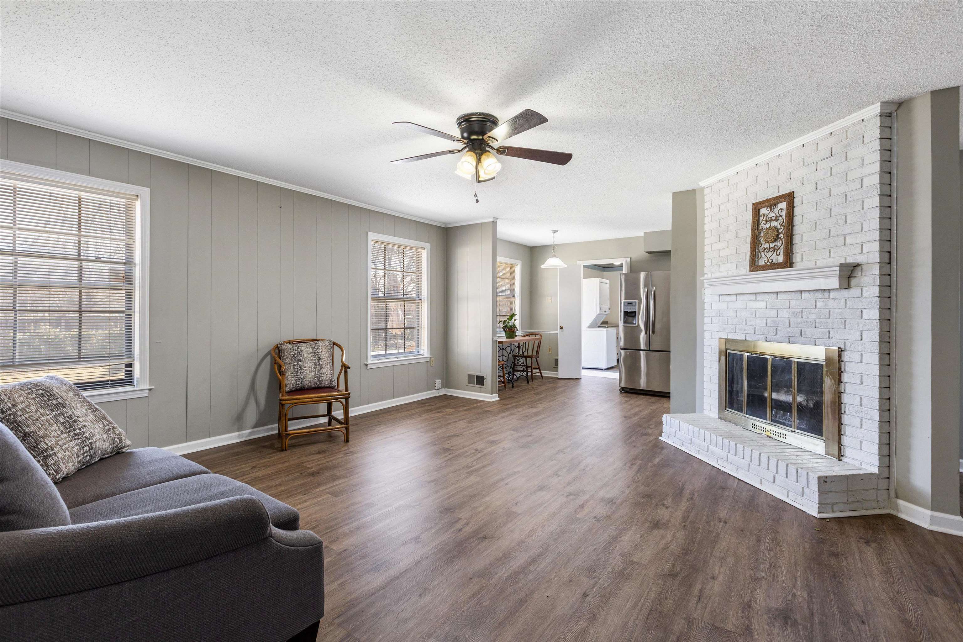 3876 Luther Road Bartlett, TN 38135 - Photo 6 of 20 Living room with ceiling fan, dark wood-style floors, a textured ceiling, a brick fireplace, and ornamental molding
