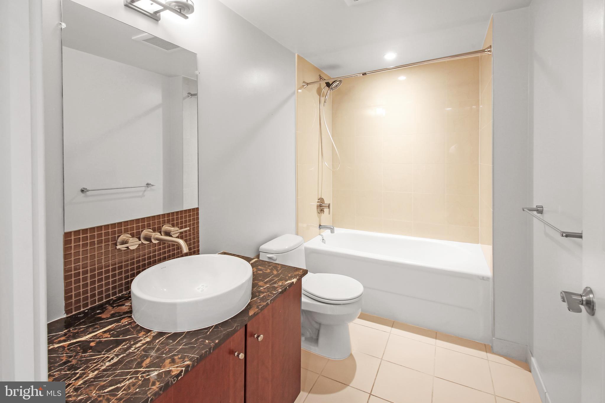 1025 First Street Southeast, Unit 612 Washington, DC 20003 - Photo 16 of 41 a bathroom with a sink toilet a mirror and shower