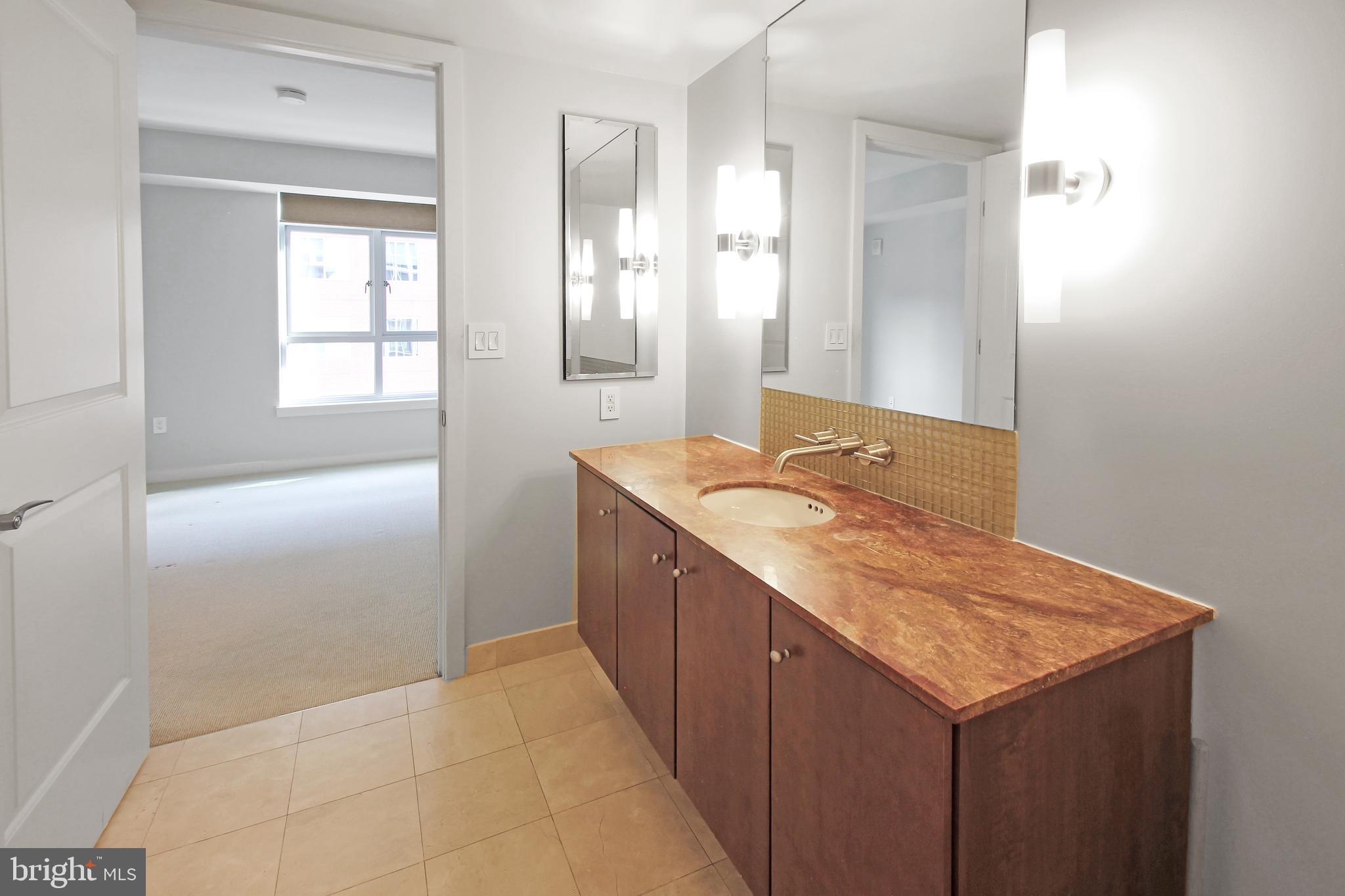 1025 First Street Southeast, Unit 612 Washington, DC 20003 - Photo 17 of 41 a bathroom with a granite countertop sink and mirror