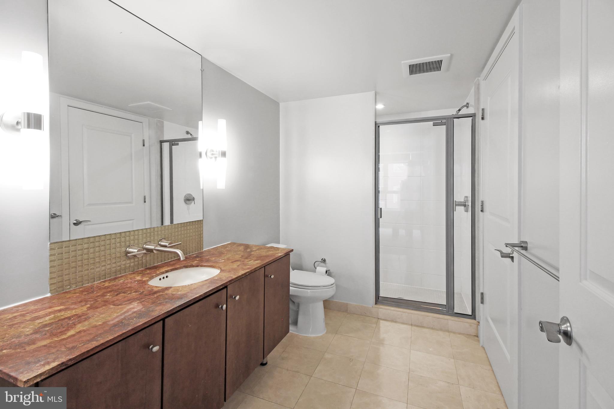 1025 First Street Southeast, Unit 612 Washington, DC 20003 - Photo 18 of 41 a bathroom with a granite countertop sink toilet and shower