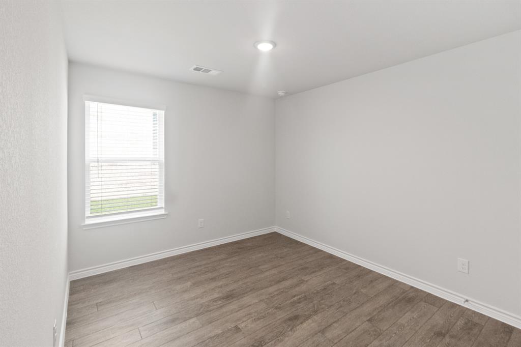 1604 Romans Road Ennis, TX 75119 - Photo 14 of 15 an empty room with wooden floor and windows