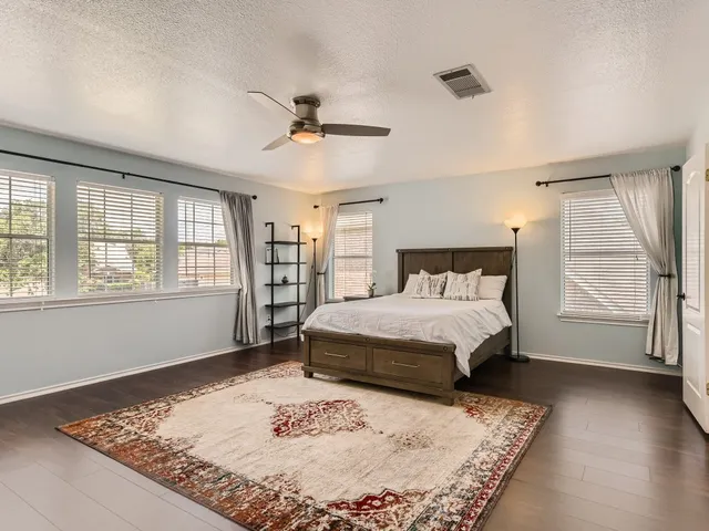 a bed sitting in a spacious bedroom next to a window