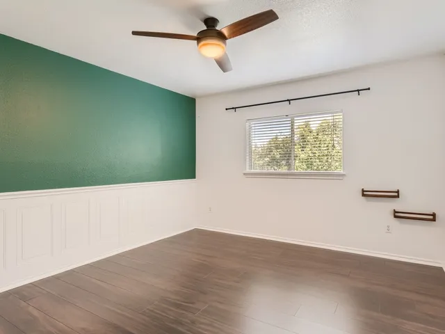 a view of empty room with wooden floor and fan