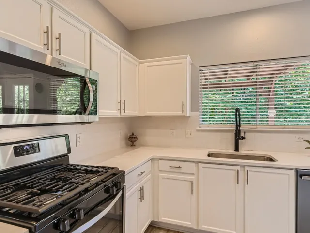 a kitchen with white cabinets a sink and a stove