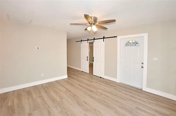 an empty room with wooden floor fan and windows