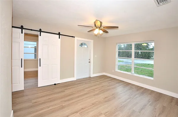 a view of empty room with wooden floor and fan