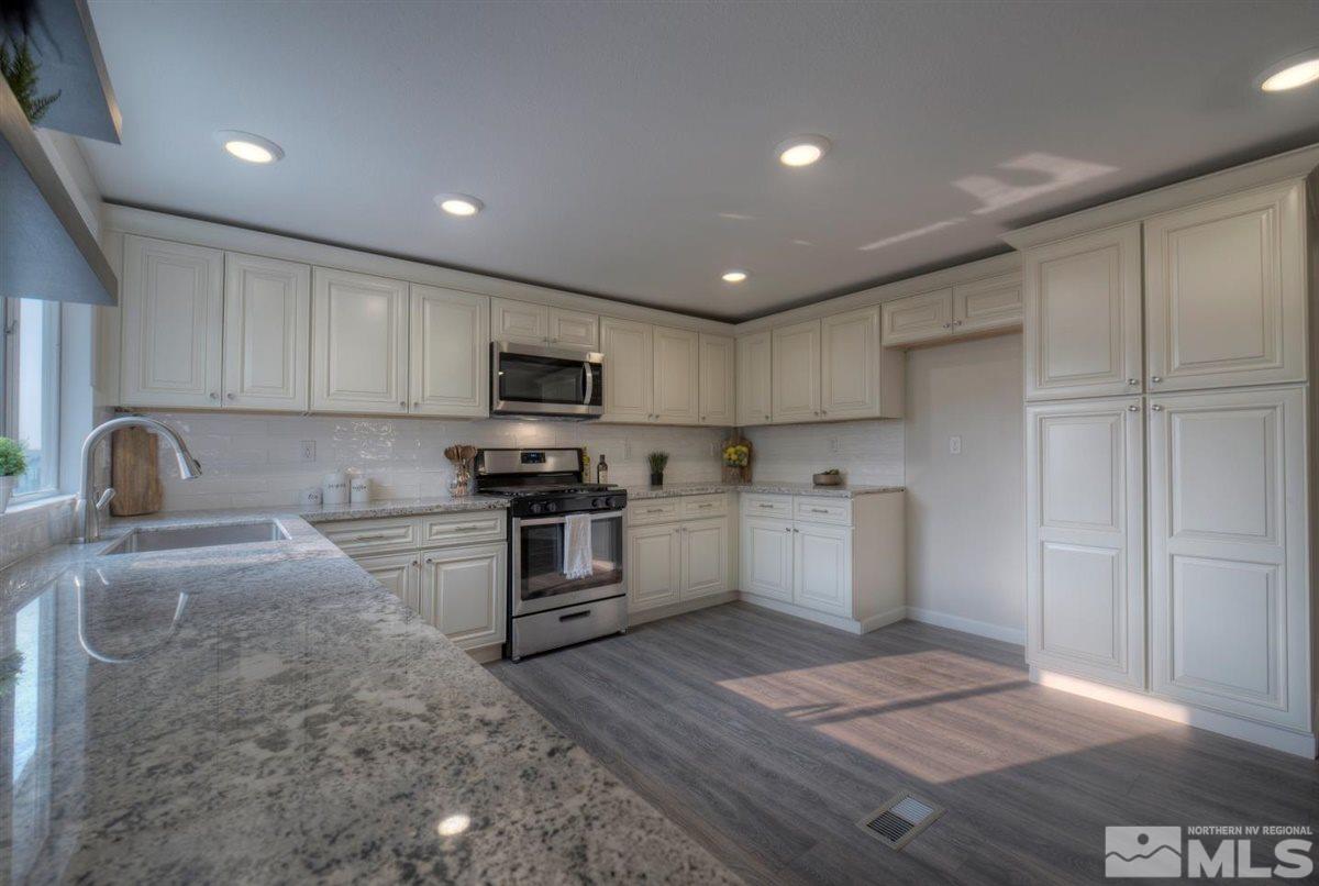 370 Scorpio Circle Reno, NV 89521 - Photo 8 of 25 a kitchen with granite countertop a stove a sink and a refrigerator