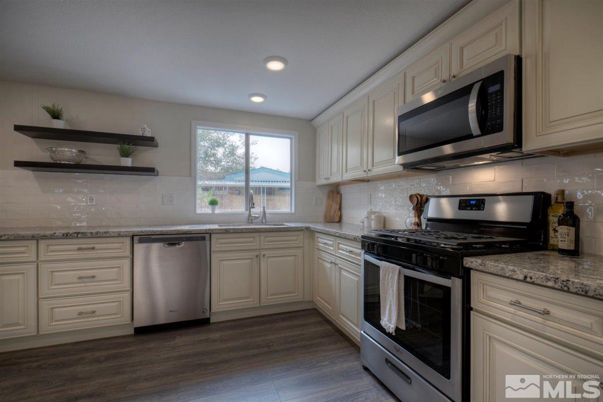 370 Scorpio Circle Reno, NV 89521 - Photo 9 of 25 a kitchen with stainless steel appliances granite countertop a stove a sink and a microwave