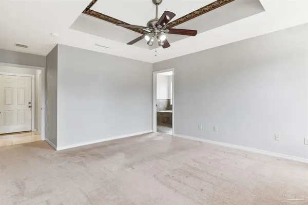 an empty room with windows and chandelier fan