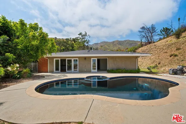 a view of house with swimming pool and outdoor seating