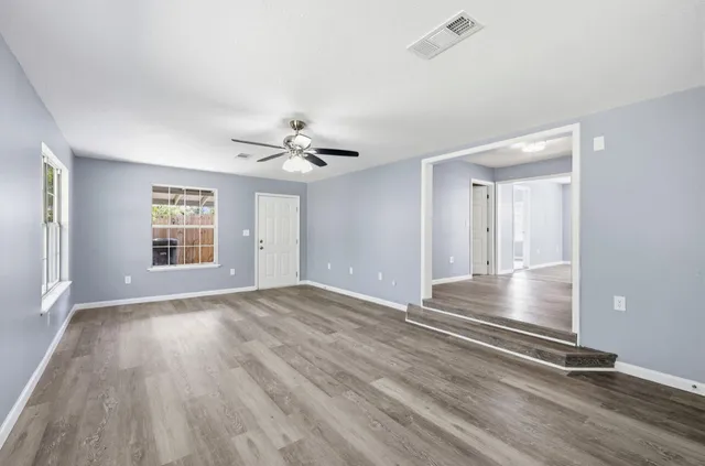 a view of an empty room with wooden floor and a window