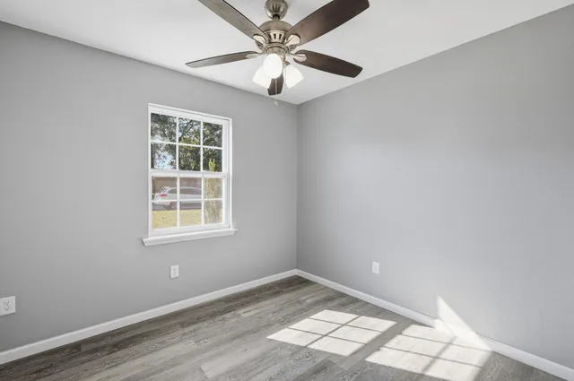 an empty room with windows and ceiling fan