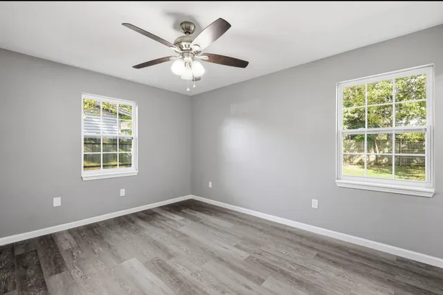 en empty room with wooden floor and windows