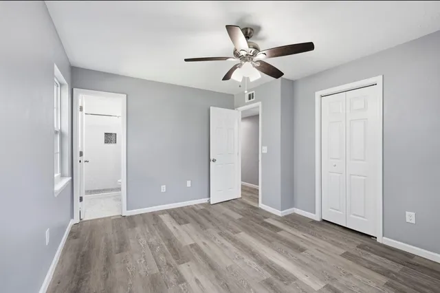 a view of empty room with wooden floor and fan