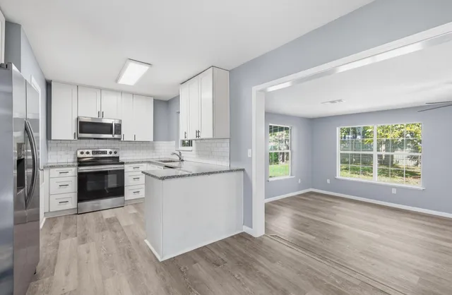 a kitchen with granite countertop a stove a sink dishwasher a refrigerator and a microwave oven with wooden floor