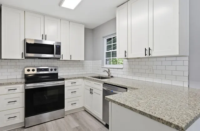 a kitchen with granite countertop a sink dishwasher stove and oven with wooden floor