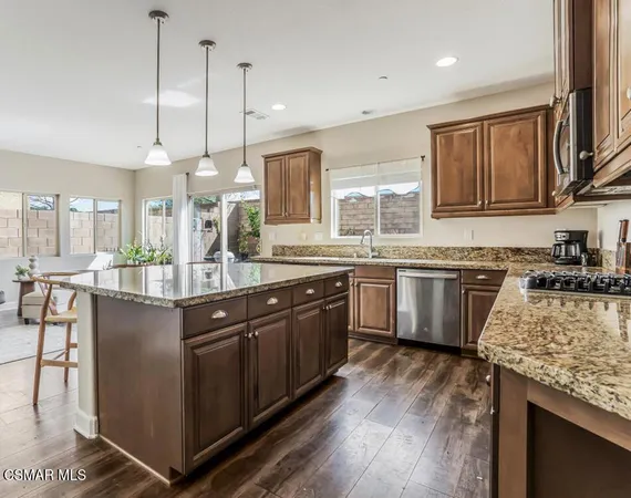 a kitchen with stainless steel appliances granite countertop a sink a stove and a wooden floors