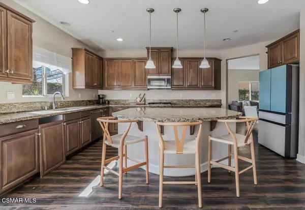 a kitchen with stainless steel appliances granite countertop a sink a stove a refrigerator and island with wooden floor