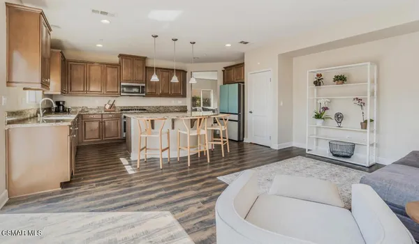 a living room with stainless steel appliances granite countertop furniture a kitchen island a stove a refrigerator a sink a counter top space and cabinets