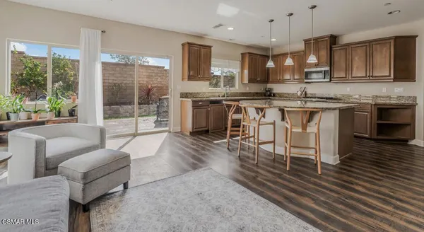 a kitchen with stainless steel appliances granite countertop a stove top oven a sink dishwasher a dining table and chairs with wooden floor