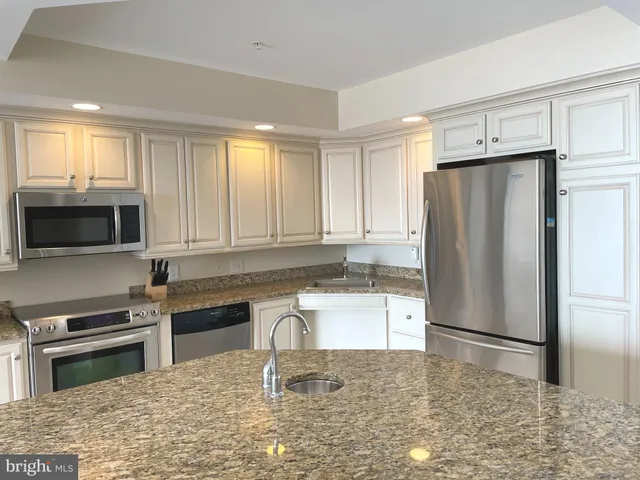 a kitchen with granite countertop a refrigerator and a stove top oven