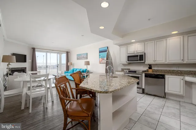 a kitchen with stainless steel appliances granite countertop a stove top oven a sink dishwasher a dining table and chairs with wooden floor