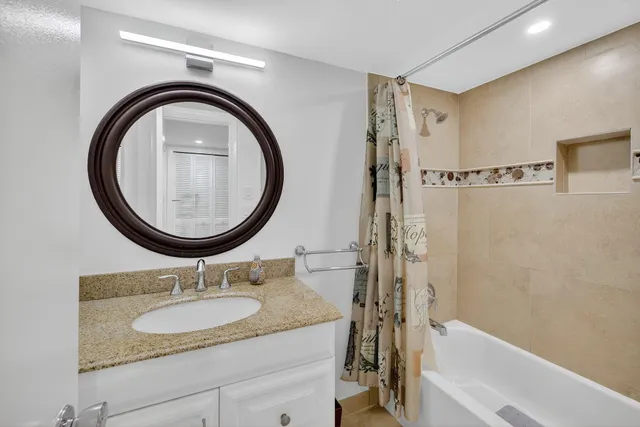 a bathroom with a granite countertop sink a mirror and a bathtub
