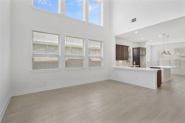 a view of an empty room with kitchen and window