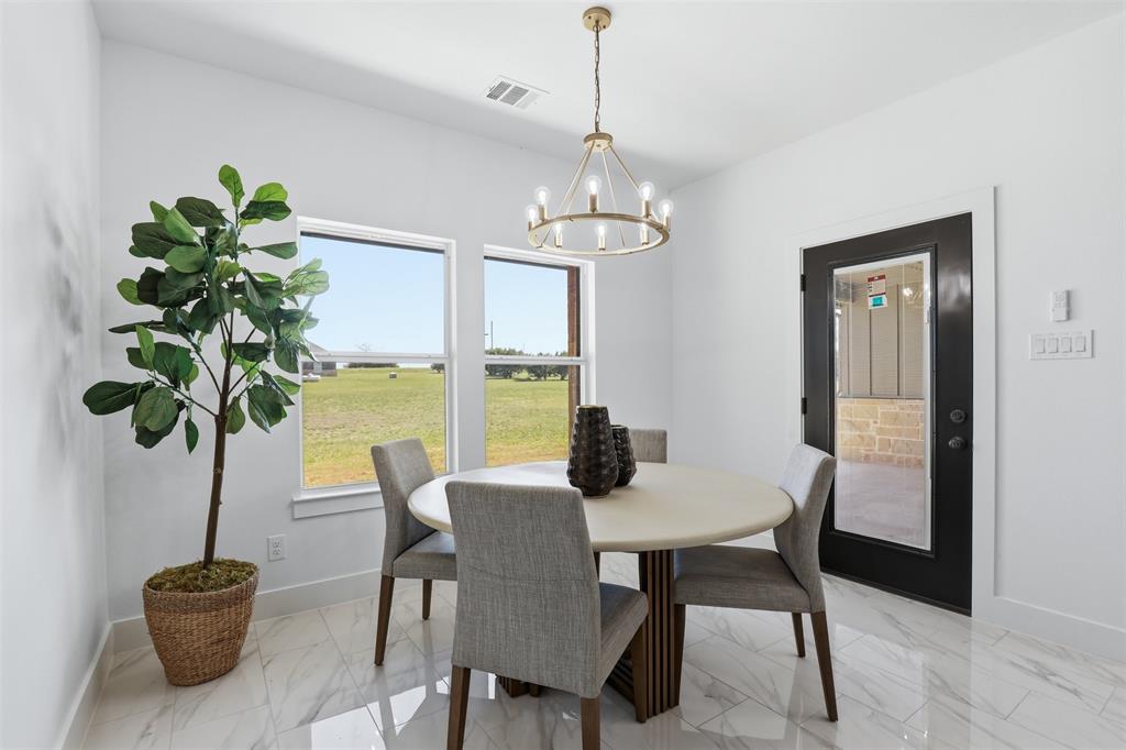 6657 Buffalo Ridge Circle Godley, TX 76044 - Photo 10 of 31 a dining room with furniture a potted plant and a chandelier