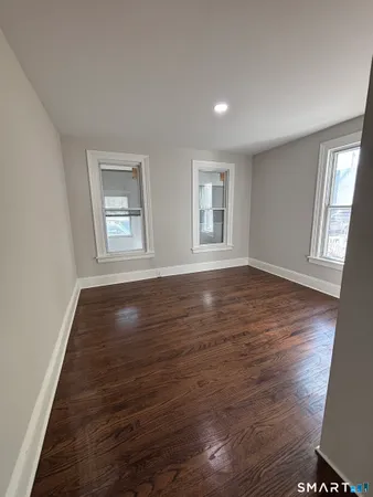 a view of an empty room with wooden floor and window