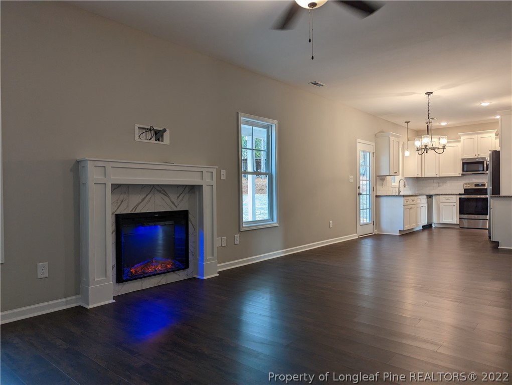 433 B & B Loop Road Raeford, NC 28376 - Photo 10 of 37 an empty room with wooden floor fire place and kitchen view