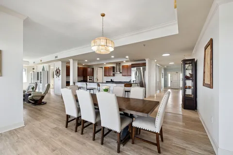 a kitchen with stainless steel appliances granite countertop a refrigerator a stove a sink a dining table and chairs with wooden floor