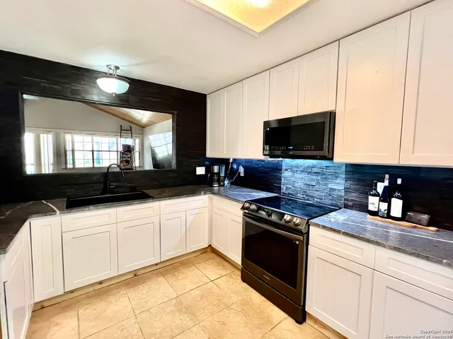 a kitchen with a sink and a stove top oven with wooden floor