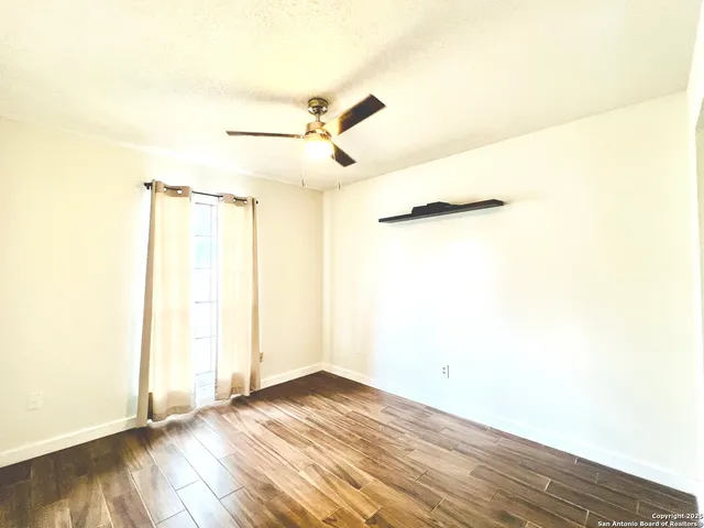 a view of a room with wooden floor and a ceiling fan