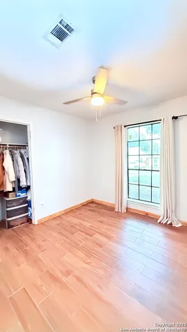 a view of empty room with wooden floor and fan