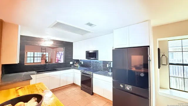 a large kitchen with kitchen island granite countertop a refrigerator and a sink