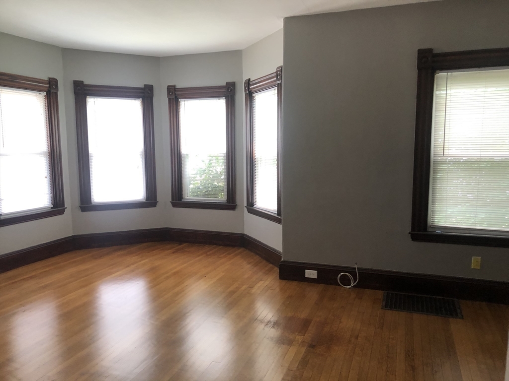 1122 Adams Street, Unit 2 Boston, MA 02124 - Photo 6 of 21 an empty room with wooden floor and windows