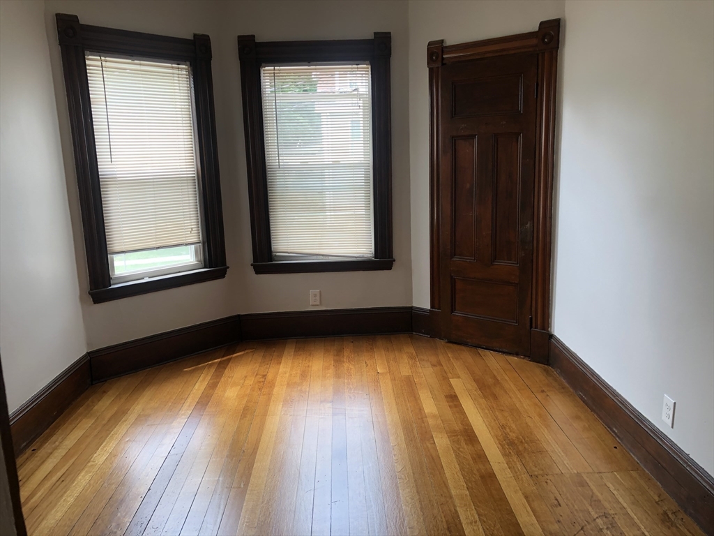 1122 Adams Street, Unit 2 Boston, MA 02124 - Photo 7 of 21 an empty room with wooden floor and windows