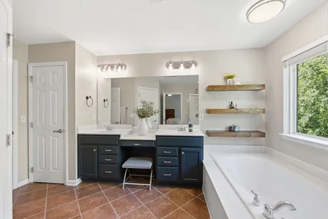 a large bathroom with a double vanity sink a mirror and a bathtub
