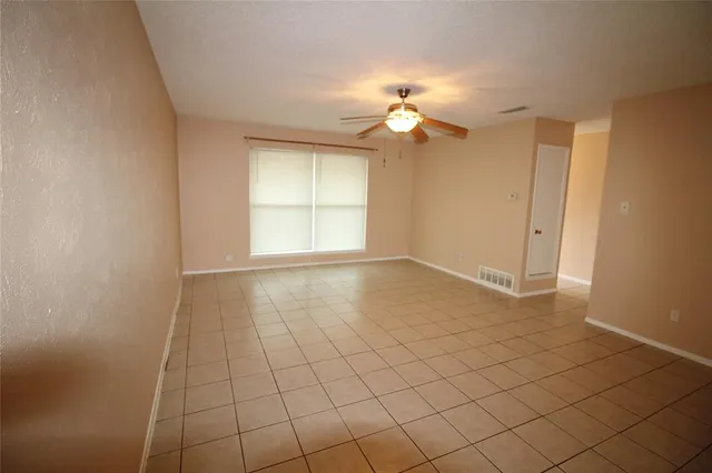 an empty room with windows and fan