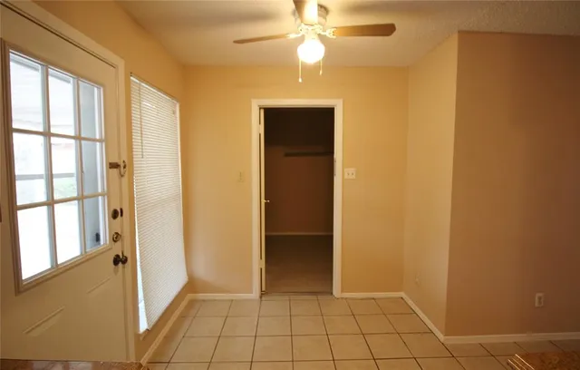 a view of an empty room with window and chandelier fan