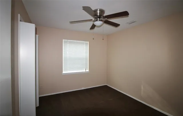 an empty room with a window and a fan