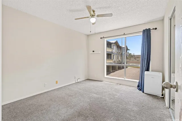an empty room with chandelier fan and windows