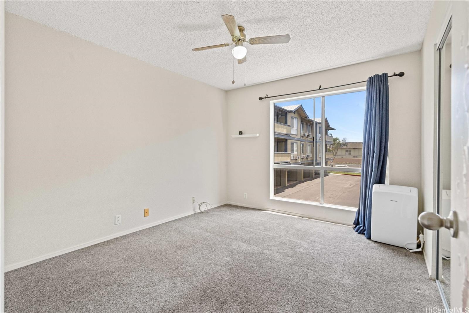91-299 Hanapouli Circle, Unit 1C Ewa Beach, HI 96706 - Photo 21 of 25 an empty room with chandelier fan and windows