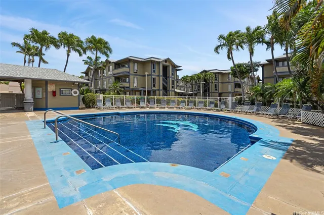 a view of a swimming pool with a lawn chairs under palm trees