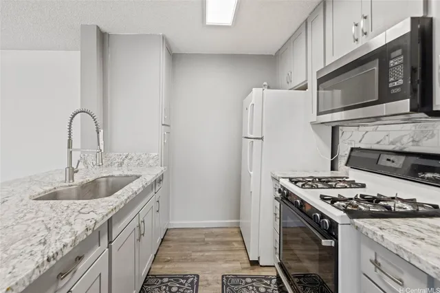 a kitchen with granite countertop a sink stove and refrigerator