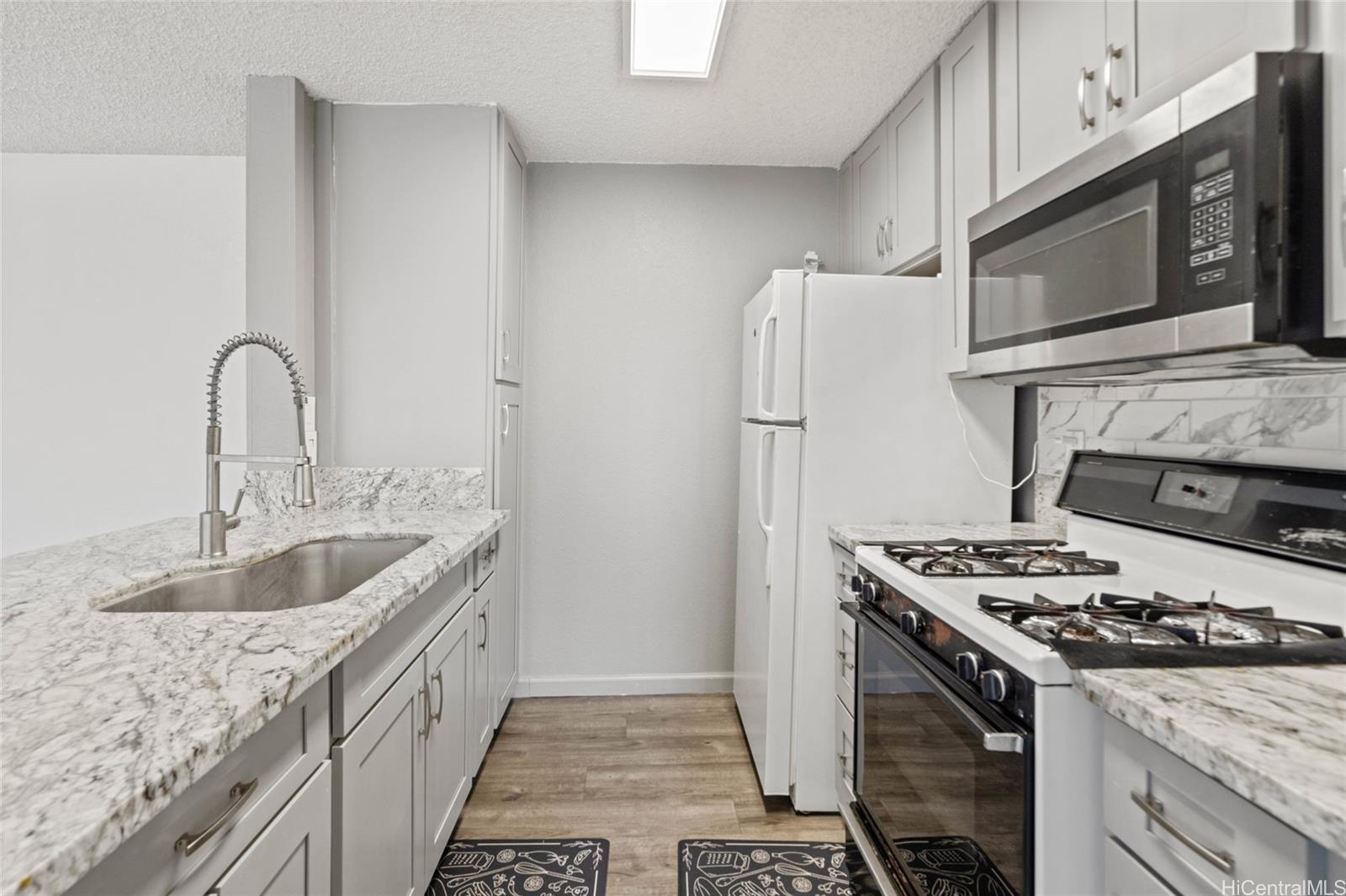91-299 Hanapouli Circle, Unit 1C Ewa Beach, HI 96706 - Photo 4 of 25 a kitchen with granite countertop a sink stove and refrigerator